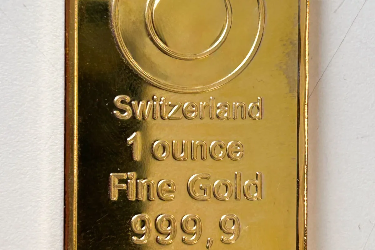 Ein nahaufgenommener Goldbarren mit der Aufschrift 'Switzerland, 1 ounce, Fine Gold, 999,9'. Der Barren hat einen glänzenden goldenen Farbton.