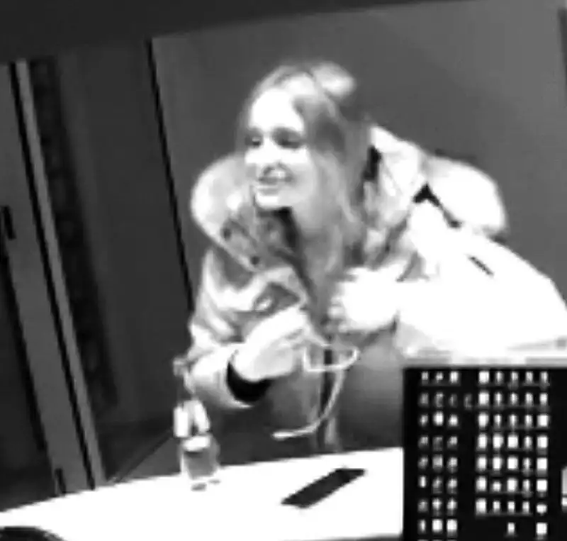 Eine Frau in einer dicken Winterjacke steht an einem Tresen. Sie scheint zu lächeln und hält ihre Hände vor sich.