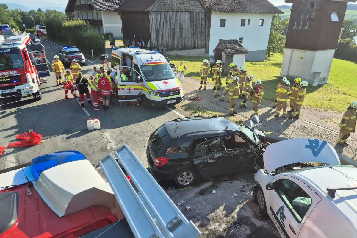 Rettungskräfte versammeln sich um zwei beschädigte Fahrzeuge an einer Straße; ein Krankenwagen und Feuerwehr sind vor Ort.