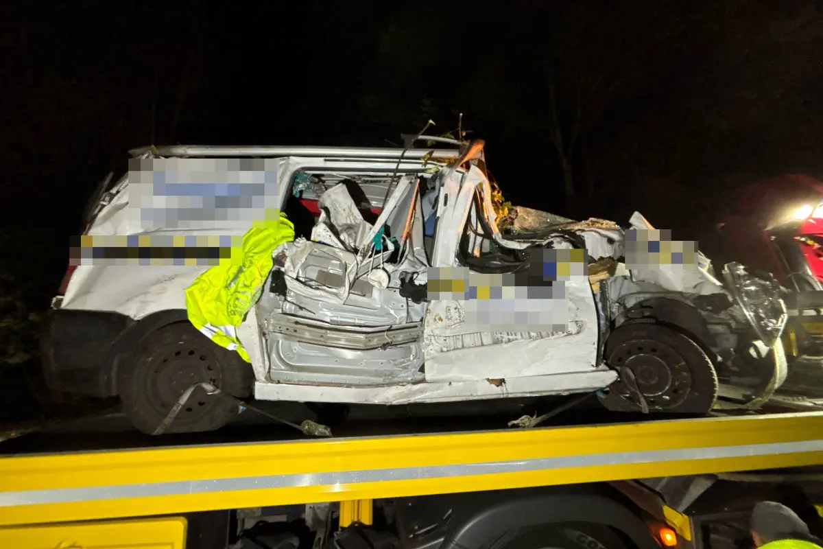 Ein stark deformierter weißer Pkw liegt quer auf einem gelben Abschleppwagen. Die Szene ist nachts aufgenommen.