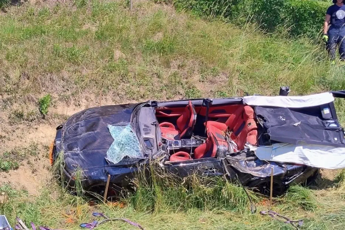 Ein schwer beschädigtes Cabriolet liegt auf der Seite in einem Graben neben einer Straße. Das Fahrzeug zeigt starke Verformungen.