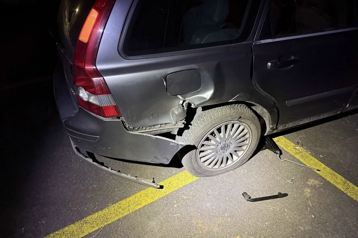 Ein dunkles Auto, dessen hinterer Kotflügel stark eingedellt ist. Der Schaden erstreckt sich über das Radhaus und die Stoßstange.