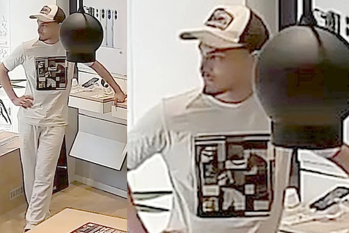 Ein männlicher Kunde steht in einem Geschäft und trägt ein weißes T-Shirt mit einem Muster sowie eine Kappe. Im Hintergrund sind Verkaufsregale zu sehen.