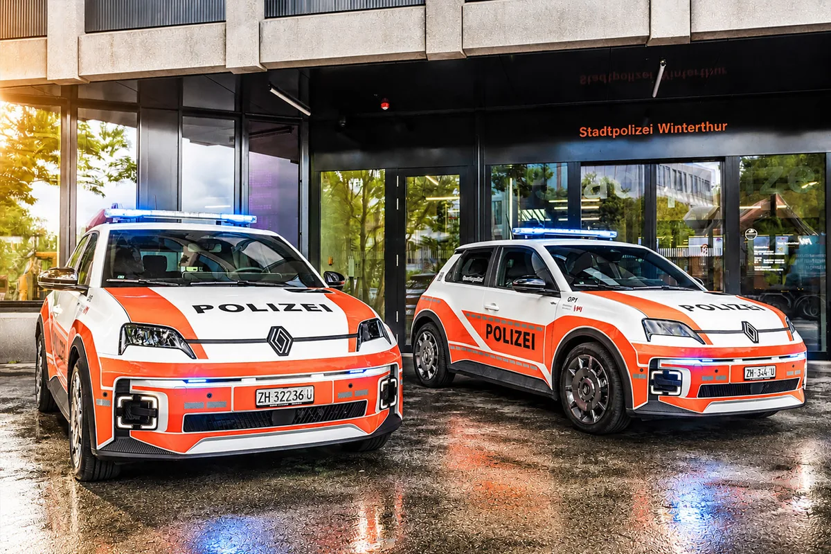 Zwei rot-weiße Polizeifahrzeuge mit der Aufschrift 'Polizei' stehen vor einem modernen Gebäude. Es ist die Stadtpolizei Winterthur erkennbar.