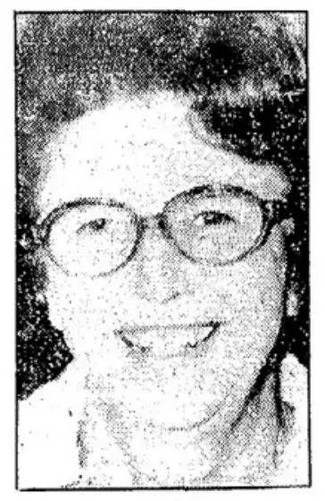 Das Bild zeigt eine ältere Person mit Brille und Lächeln in einem körnigen Schwarzweiß-Porträt.