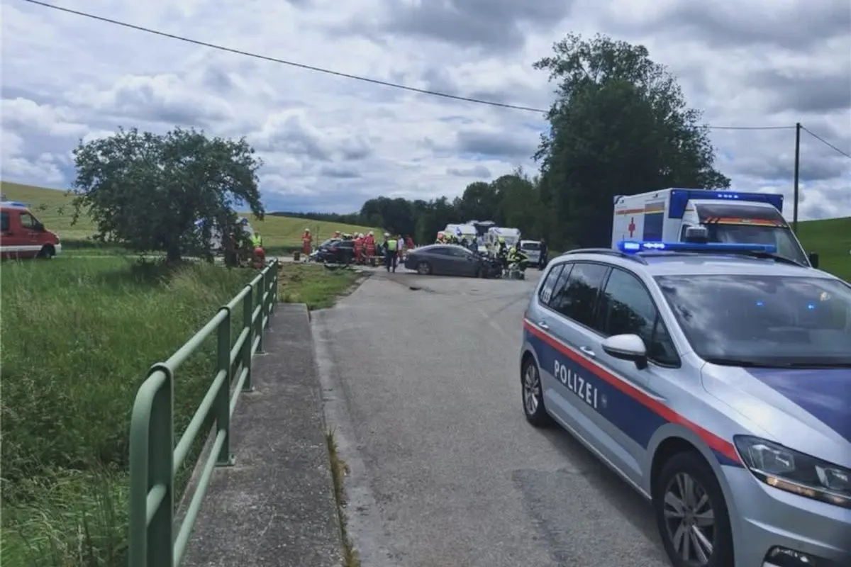 Ein Polizeifahrzeug und mehrere Rettungsfahrzeuge stehen an einer Unfallstelle auf einer Landstraße, umgeben von Einsatzkräften.