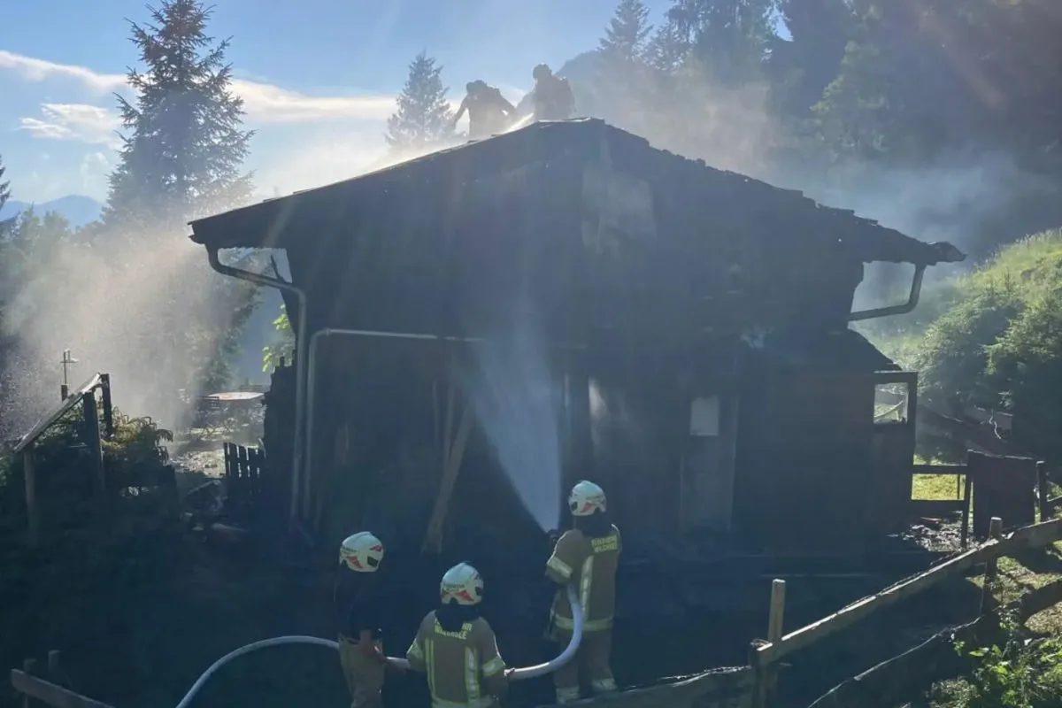Feuerwehrleute bekämpfen einen Brand auf dem Dach eines Hauses. Rauch umhüllt das Gebäude bei Tageslicht.