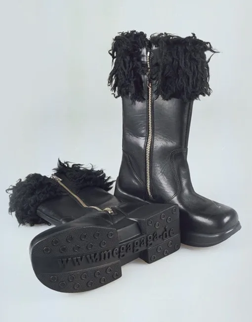 Ein Paar schwarze Lederstiefel mit flauschigem Rand und Reißverschluss, liegend auf einer neutralen Fläche.