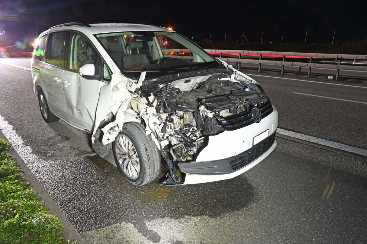 Ein weißer VW mit schwerem Frontschaden steht auf einer Autobahn. Teile der Motorhaube fehlen.