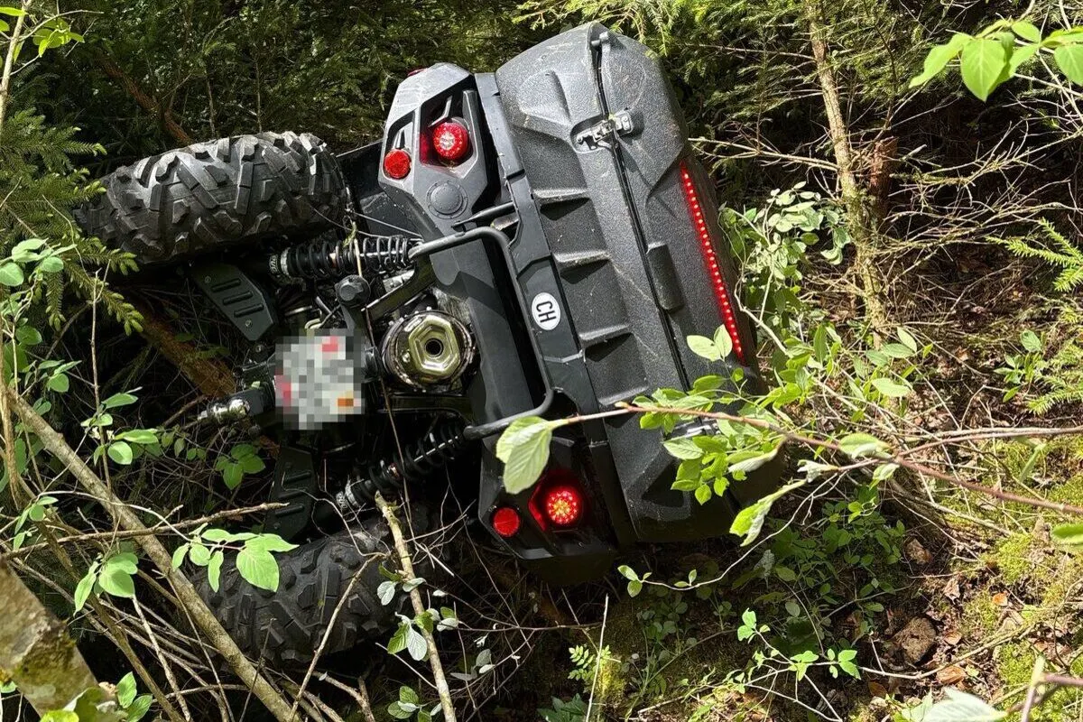 Ein Quad liegt seitlich umgekippt im dichten Unterholz eines Waldgebiets. Das Fahrzeug zeigt rote Rücklichter und hat deutliche Gebrauchsspuren.