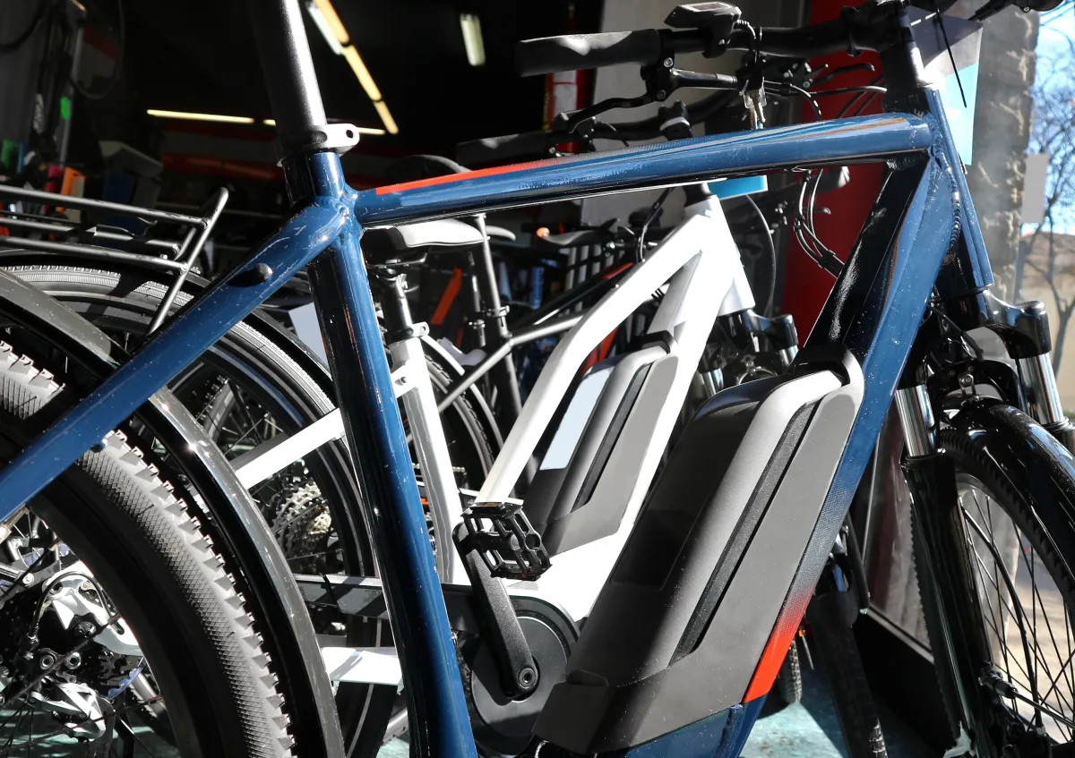 In einem Fahrradgeschäft sind mehrere E-Bikes zu sehen, die dicht beieinander stehen. Sie sind modern und scheinen auf ihren Einsatz zu warten.
