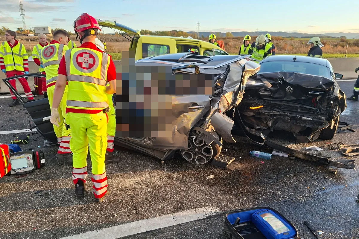 Mehrere stark beschädigte Fahrzeuge auf einer Straße, umgeben von Rettungskräften in gelben Westen und Helmen im Einsatz.
