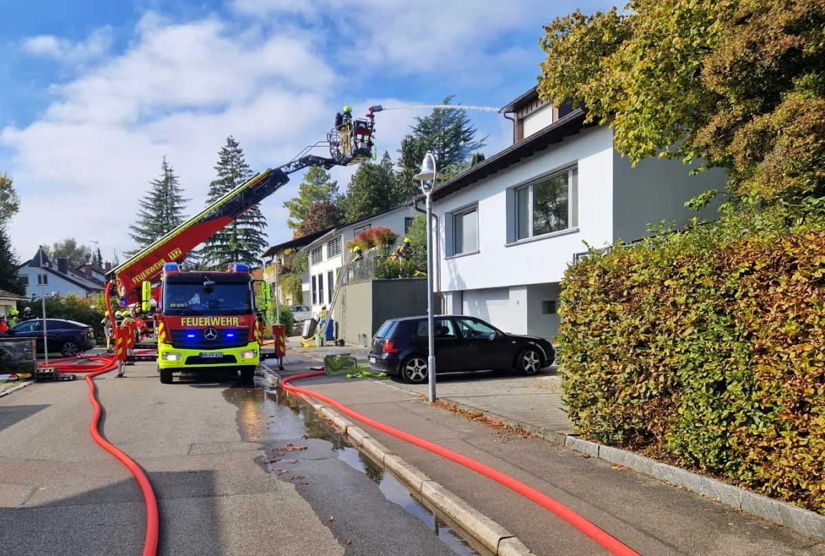Ein Feuerwehrfahrzeug mit ausgestrecktem Leiterwagen steht vor einem Wohnhaus. Feuerwehrleute sind im Einsatz.