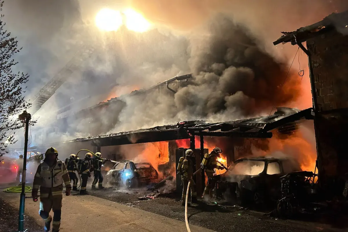 In der Nacht bekämpft die Feuerwehr einen massiven Brand in einem Parkhaus, umgeben von starkem Rauch und Flammen.