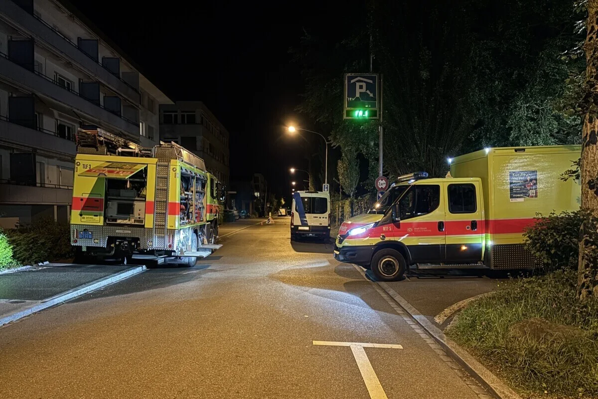 Mehrere Feuerwehrfahrzeuge stehen nachts mit eingeschaltetem Blaulicht in einer Wohnstraße. Die Straße ist leer und schwach beleuchtet.
