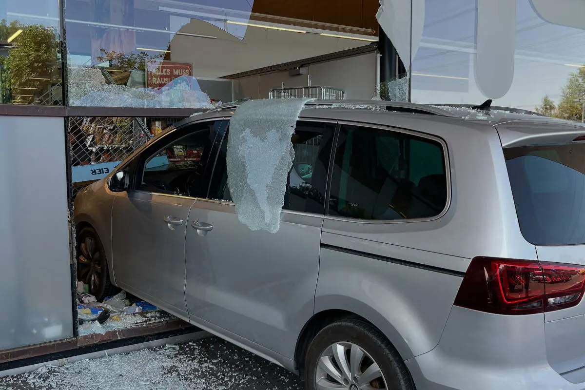 Ein silberfarbenes Auto ist in die Schaufensterscheibe eines Ladens gefahren. Überall liegen Glasscherben verstreut.