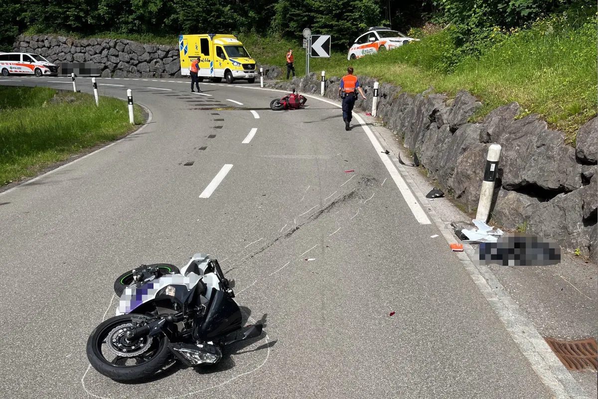 Auf einer kurvigen Straße sind zwei Motorräder umgestürzt. Ein Polizeiauto ist im Hintergrund zu sehen, umgeben von Beamten.