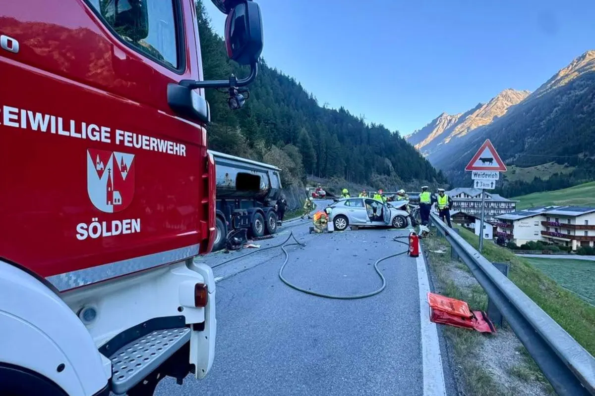 Auf einer Landstraße stehen Einsatzkräfte der Feuerwehr neben zwei beschädigten Fahrzeugen. Ein Feuerwehrfahrzeug und Bergegerät sind sichtbar.