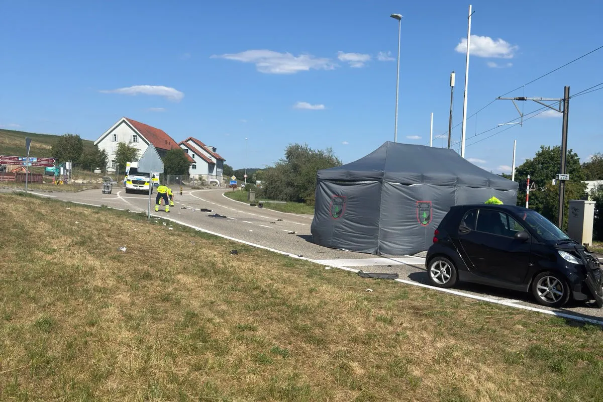 Ein Unfall auf einer Landstraße zeigt ein schwarzes Auto und ein graues Zelt. Beamte sind vor Ort, um den Unfall zu untersuchen.
