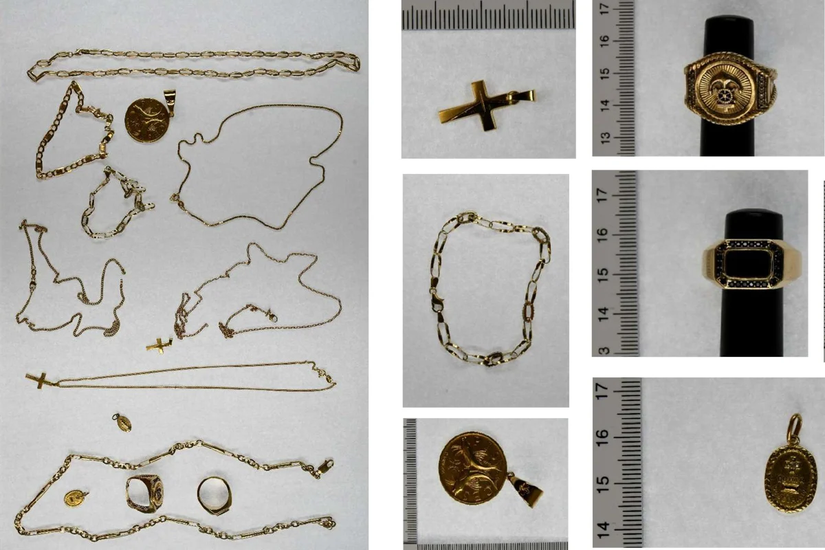 Eine Sammlung von goldenen Halsketten, Anhängern und Ringen liegt auf einem hellen Hintergrund. Ein Maßstab dient zur Größenbestimmung.