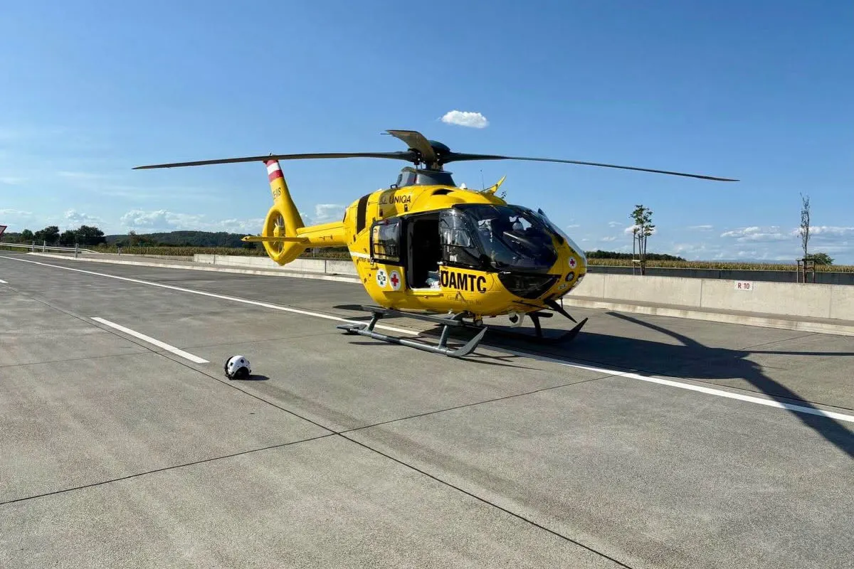 Ein gelber Rettungshubschrauber steht auf einer leeren Autobahn. Der Himmel ist klar und sonnig.