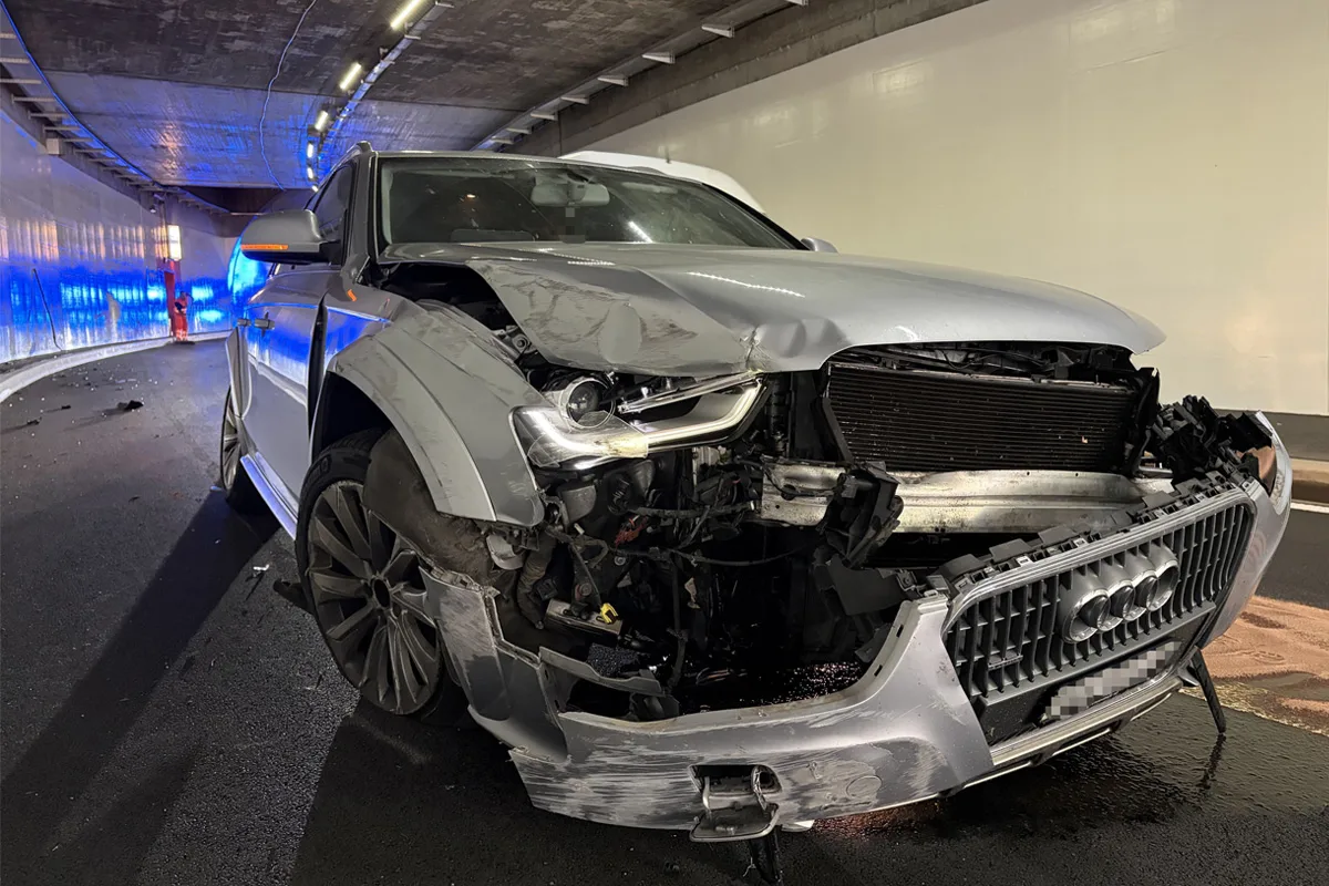 Ein stark beschädigter Audi steht in einem Tunnel. Die Front des Fahrzeugs ist erheblich deformiert.