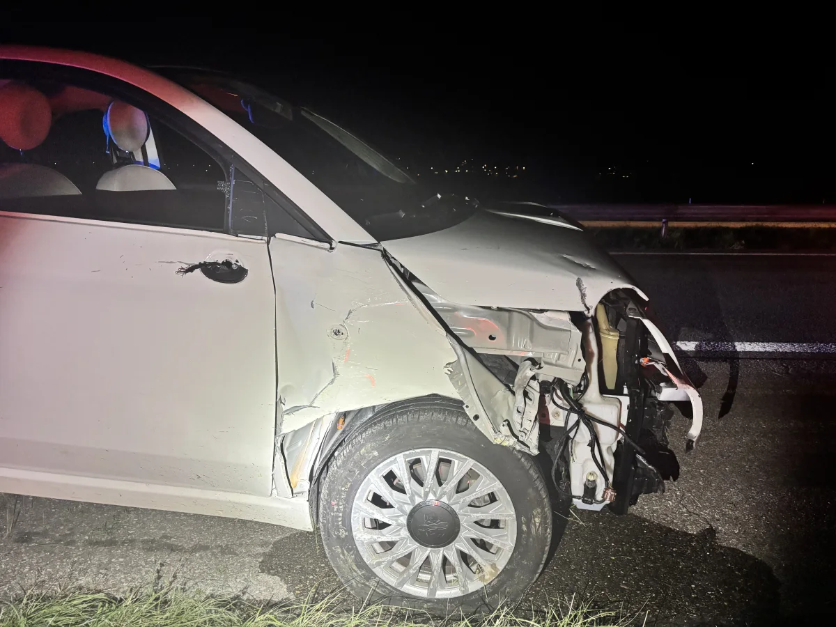 Ein weißes Auto zeigt erhebliche Frontschäden nach einem Unfall. Das Bild ist nachts aufgenommen worden, und das Fahrzeug steht auf einer Straße.