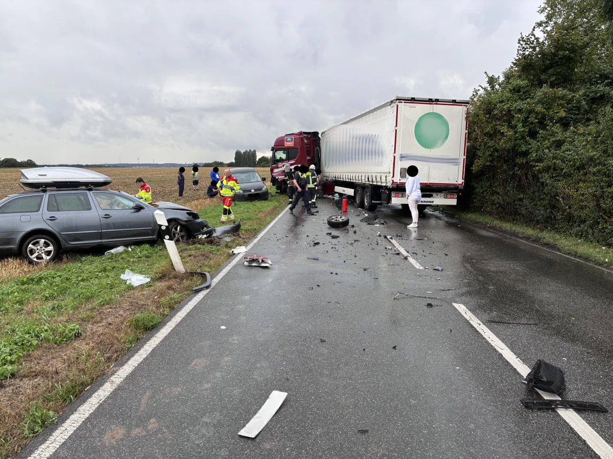 Ein Lkw ist mit einem Pkw auf einer nassen Landstraße kollidiert, mehrere Einsatzkräfte sind vor Ort.