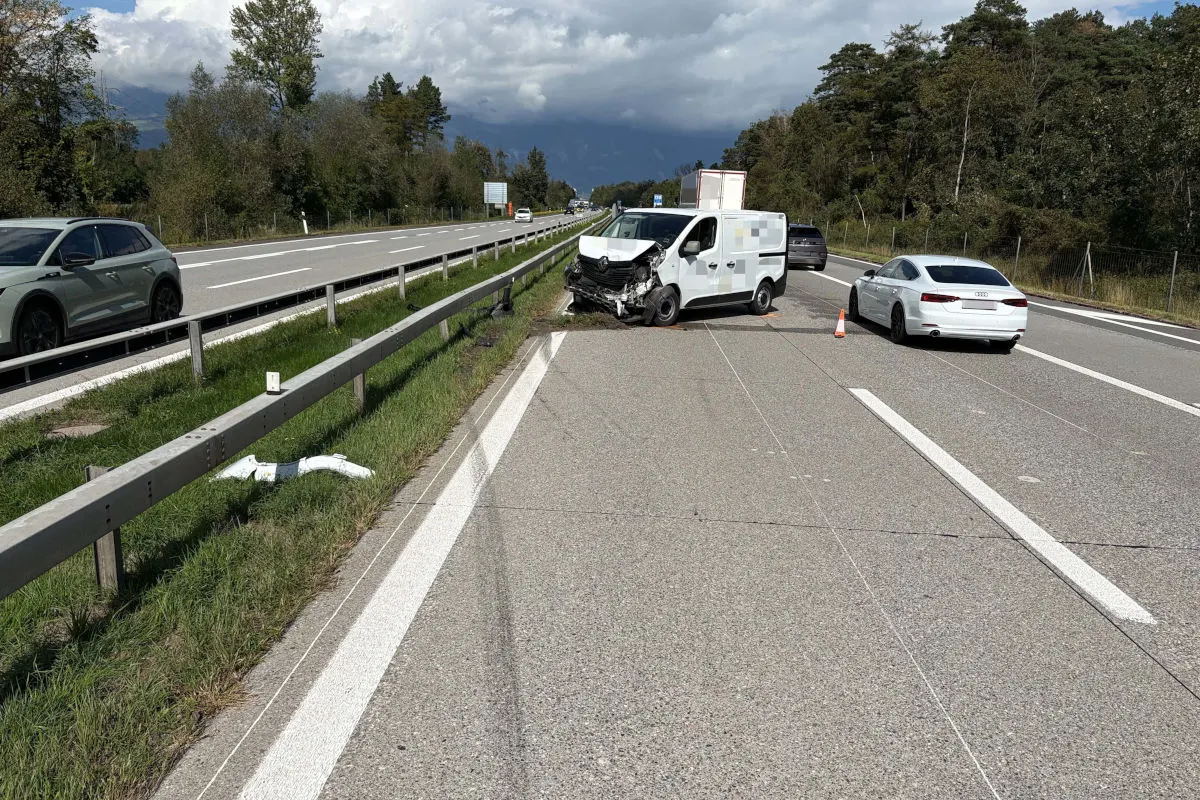 Ein weißer Kleintransporter steht nach einem Unfall mit deutlichen Frontschäden auf der Autobahn. Daneben ein weißes Auto und ein orangefarbener Verkehrskegel.