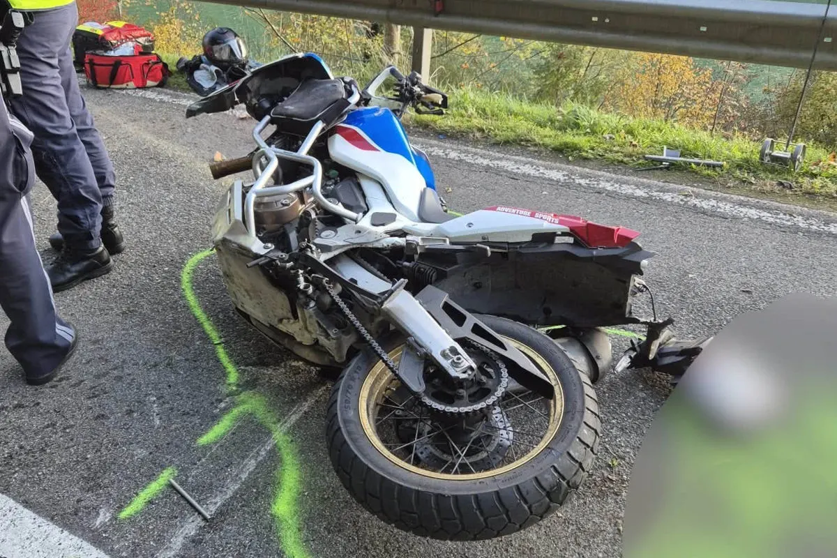 Ein beschädigtes Motorrad liegt auf einer asphaltierten Straße in der Nähe einer Leitplanke. In der Umgebung sind Polizeikräfte und Absperrungen erkennbar.