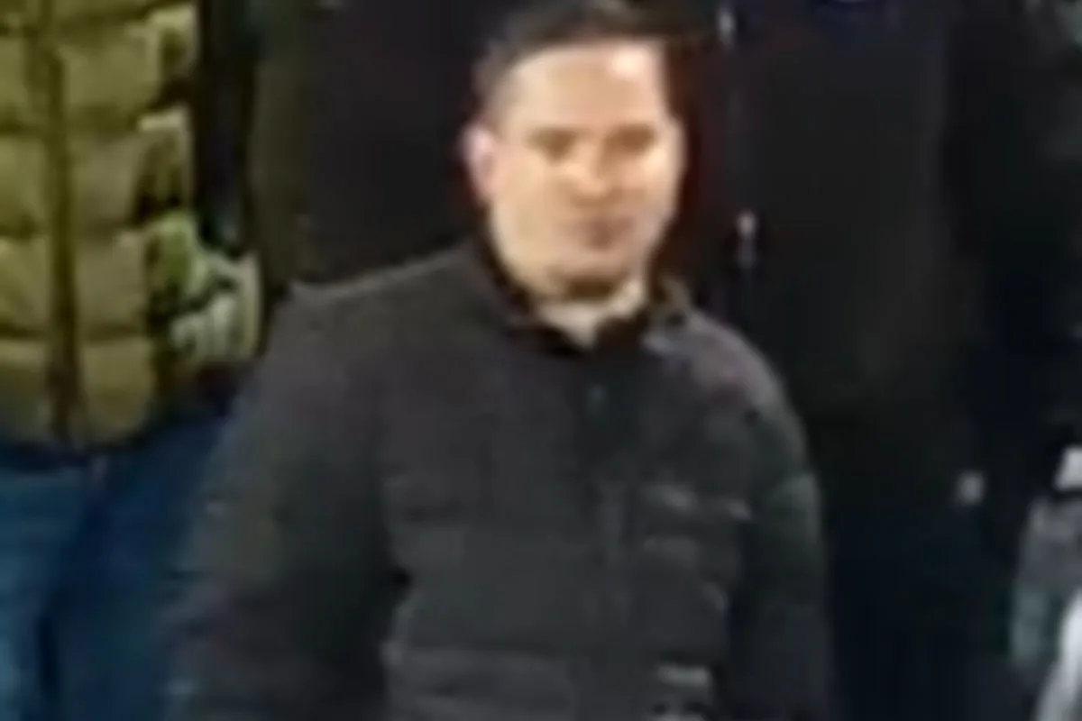 Das Bild zeigt eine verschwommene Nahaufnahme eines Mannes, der eine dunkle Jacke trägt. Der Hintergrund und andere Details sind undeutlich.