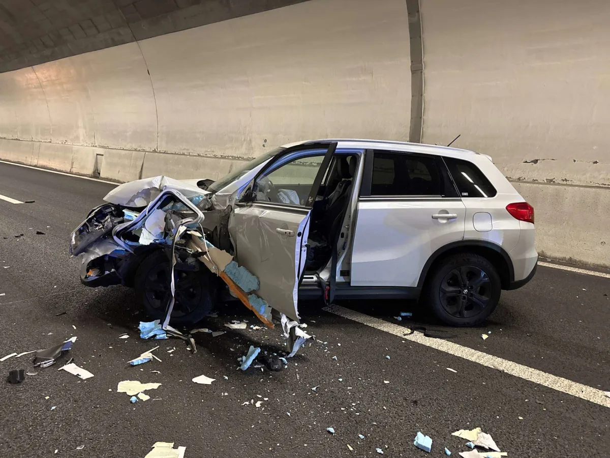 Ein weißer SUV steht stark beschädigt mit offener Tür in einem Tunnel. Trümmerteile sind vor dem Fahrzeug verteilt.