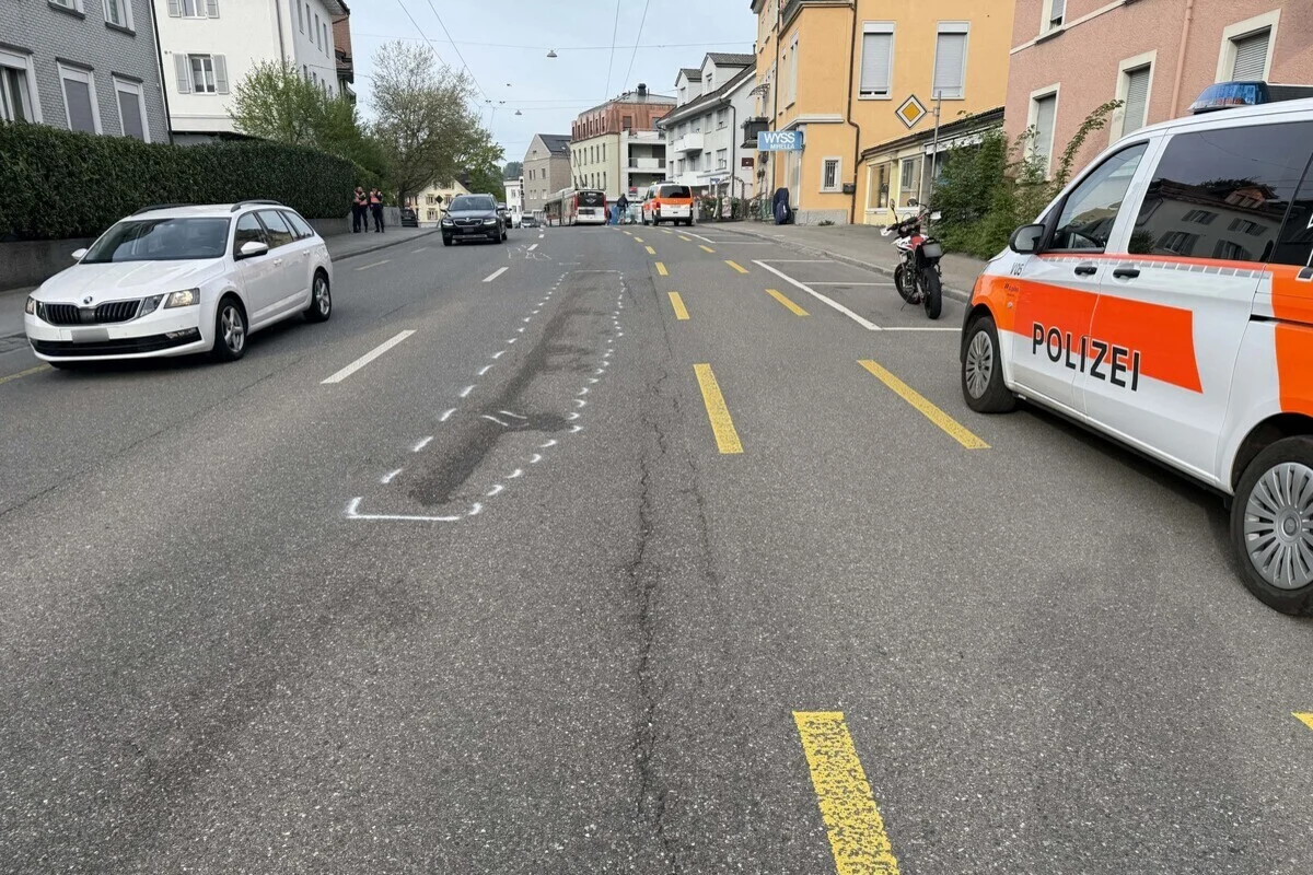 Eine städtische Straße mit einem markierten Polizeifahrzeug auf der rechten Seite und mehreren Autos, die unterwegs sind. Es ist tagsüber und die Umgebung wirkt urban.