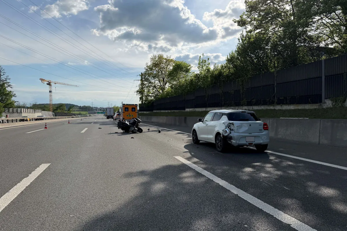Auf einer Autobahn ist ein beschädigtes weißes Auto zu sehen, daneben steht ein Rettungswagen. Trümmer liegen auf der Fahrbahn.