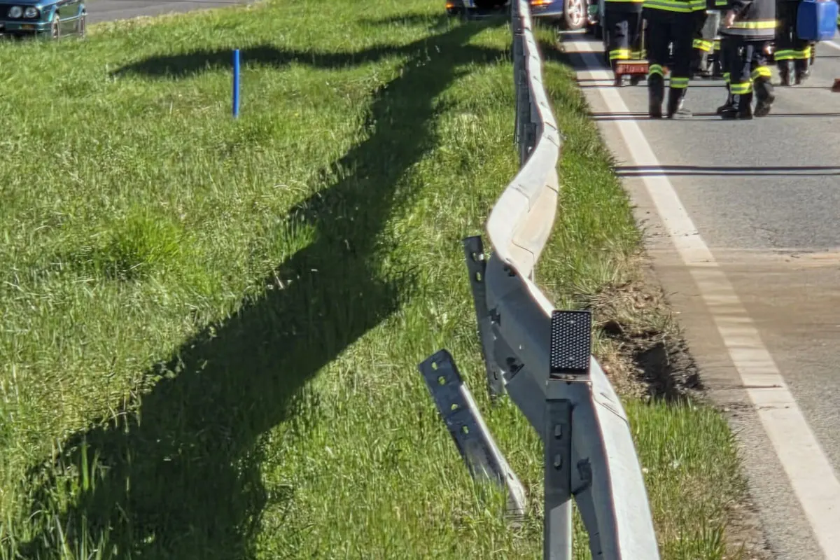 Mehrere Rettungskräfte in reflektierenden Uniformen stehen auf einer Straße neben einer beschädigten Leitplanke. Ein Grünstreifen erstreckt sich links.