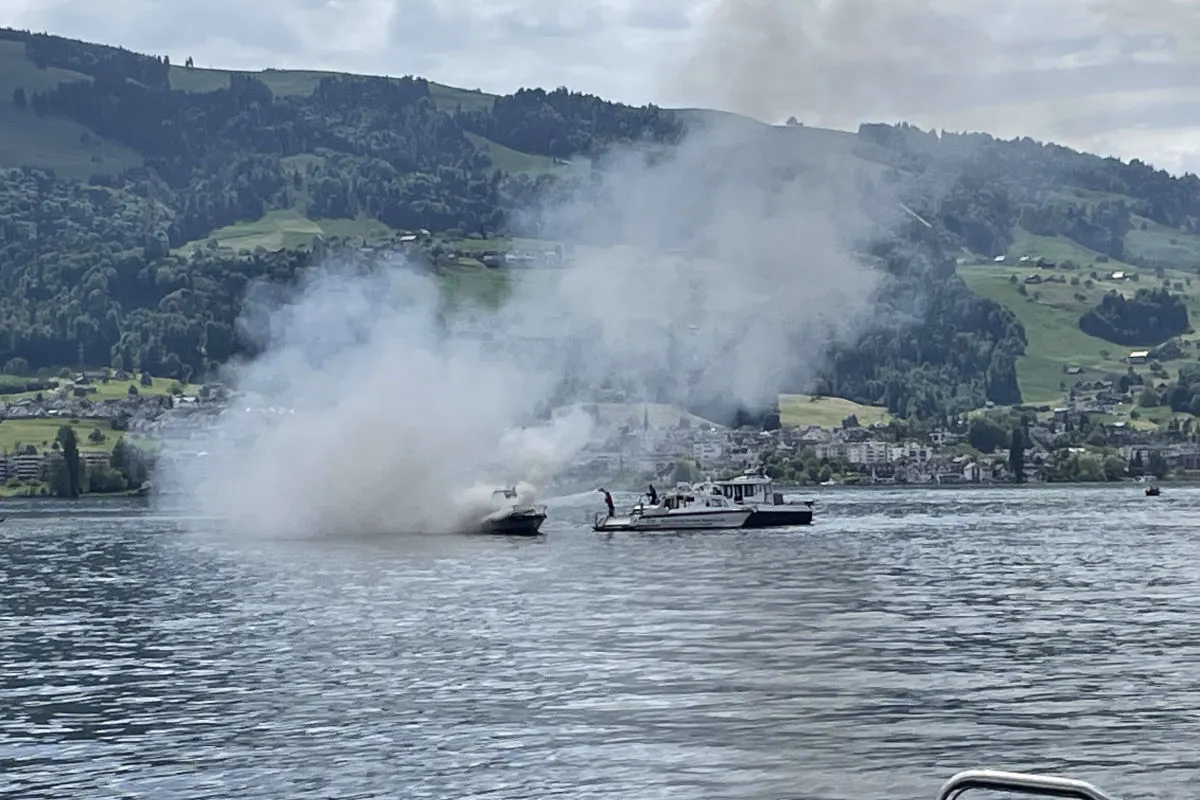 Zwei Boote befinden sich auf einem See, wobei eines stark raucht. Im Hintergrund ist eine bergige Landschaft zu sehen.