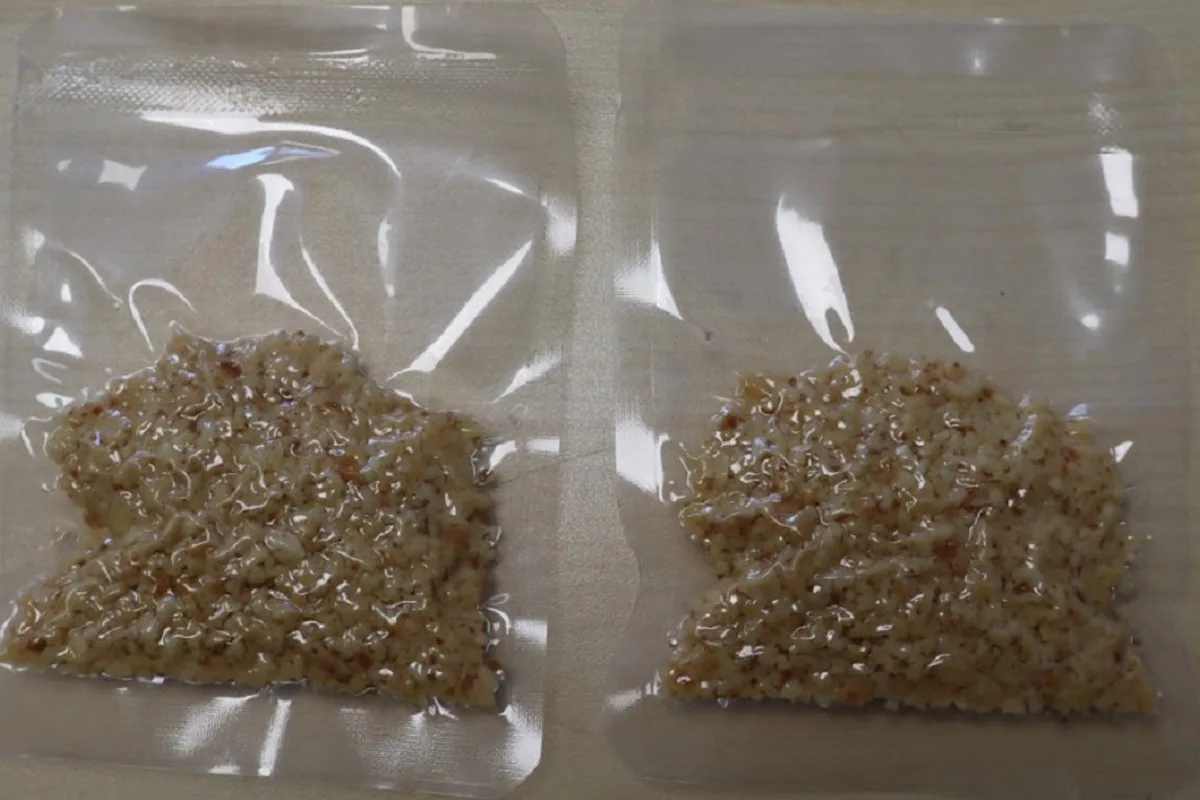 Zwei durchsichtige Plastikbeutel liegen auf einem Tisch, jeder enthält eine krümelige, beigefarbene Substanz.