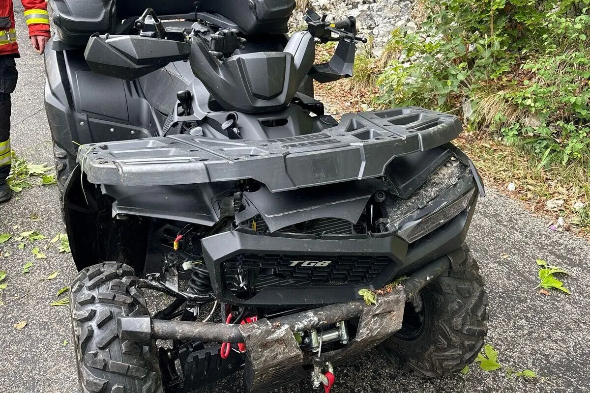 Ein Quad mit stark beschädigter Vorderseite steht auf einer asphaltierten Straße, rechts grünt die Vegetation.