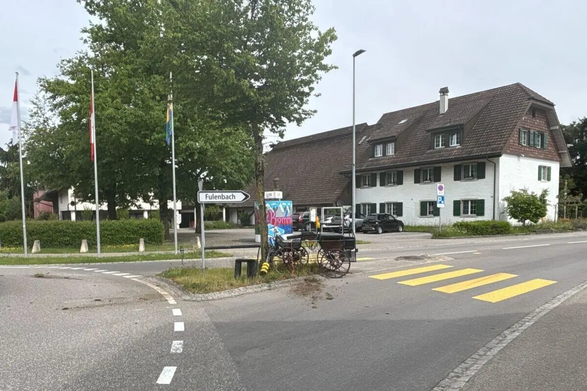 Ein altes Fahrzeug steht im Zentrum eines Kreisverkehrs neben einem Schild mit der Aufschrift Fulenbach. Im Hintergrund sind Bäume und Gebäude zu sehen.