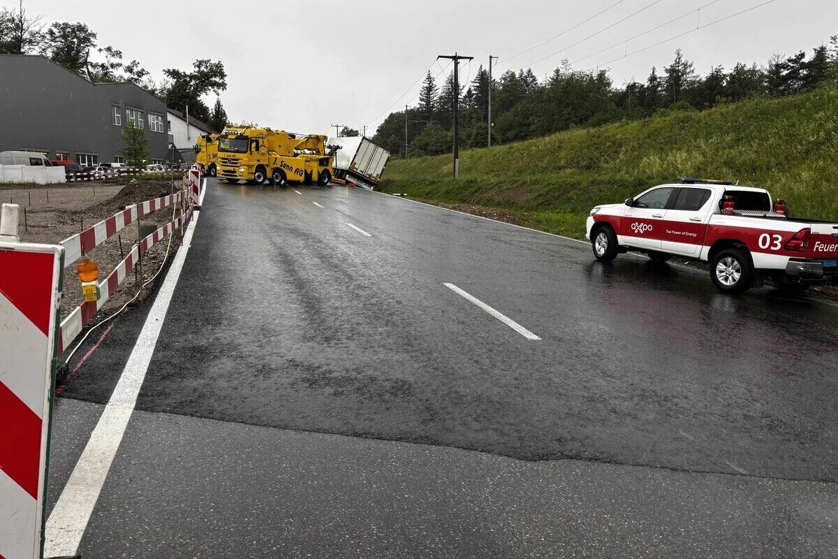 Auf einer Straße hebt ein gelber Bergungstruck einen verunfallten LKW an. Die Straße ist nass und abgesichert.