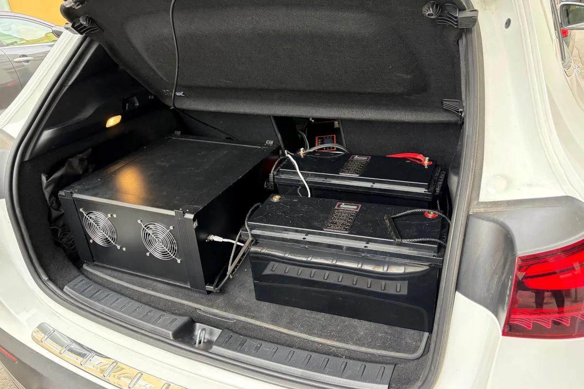 Ein geöffneter Kofferraum eines Autos mit schwarzen, technischen Geräten, einschließlich Batterien und Elektronik.