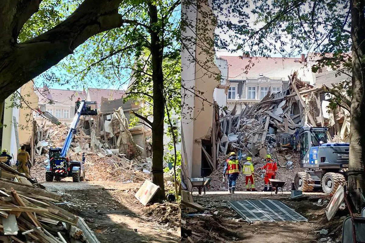 Ein Gebäude ist eingestürzt und Trümmer sind weit verstreut. Einsatzkräfte und Baumaschinen befinden sich am Einsatzort, um die Lage zu sichern.