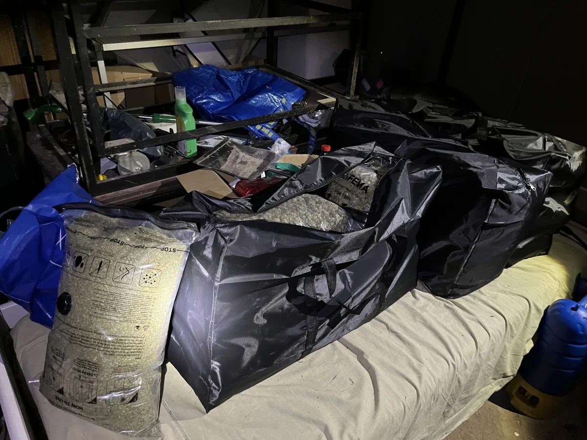 In einem dunklen Lagerraum sind mehrere große schwarze Taschen zu sehen. Daneben befinden sich blaue Säcke und diverse Behälter.