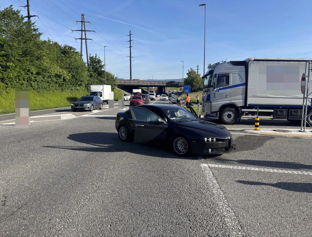 Ein schwarzes Auto steht auf einer Autobahnabzweigung, während ein grauer LKW daneben steht. Der Himmel ist klar und es ist tagsüber.
