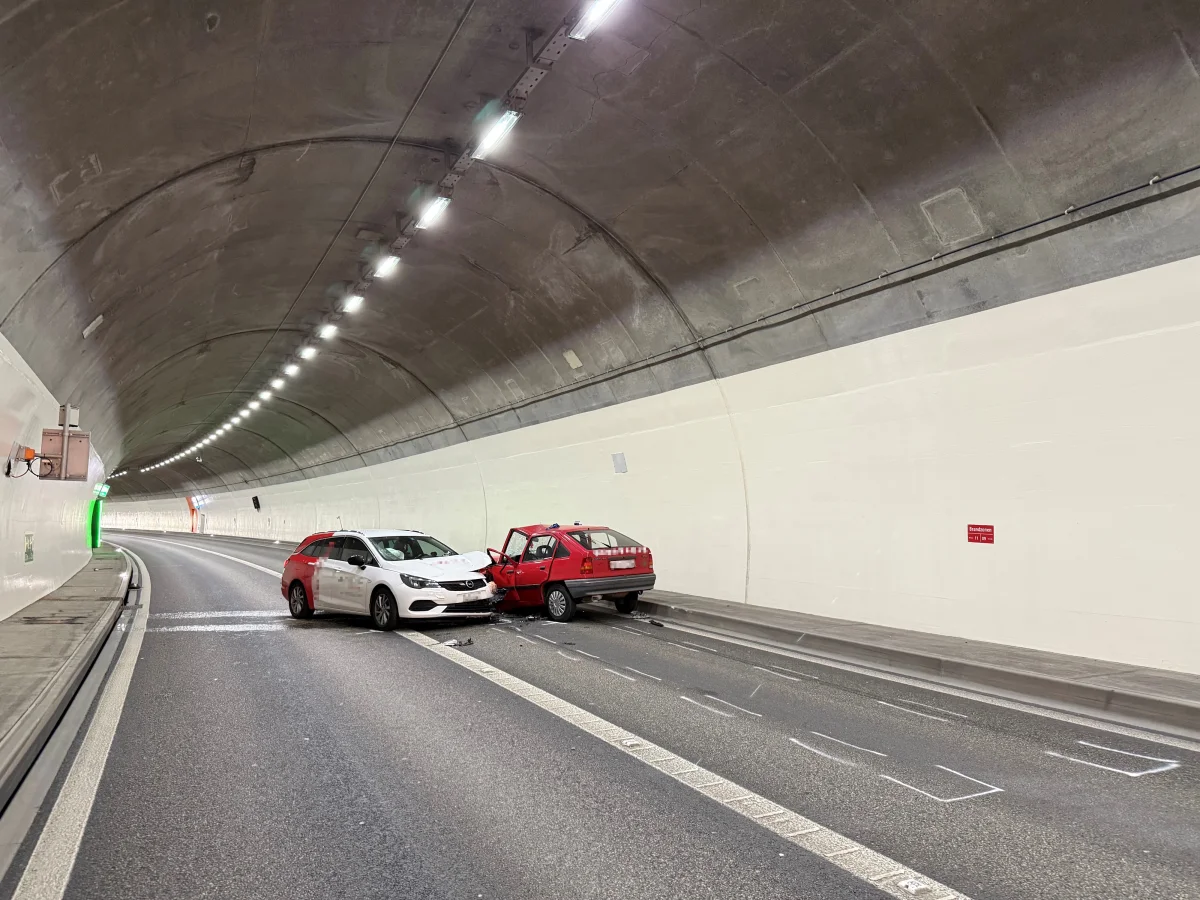 In einem Tunnel sind zwei Autos aufeinandergeprallt, ein weißes und ein rotes Fahrzeug. Personen sind nicht sichtbar.