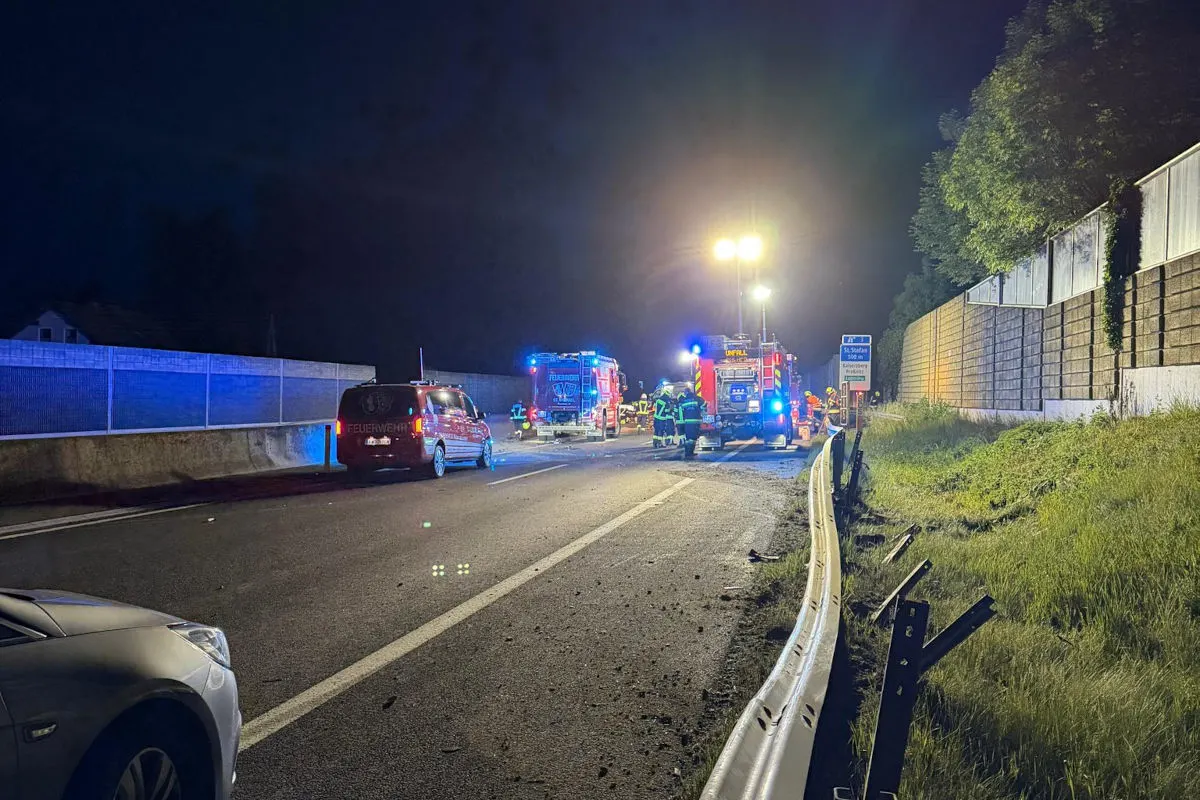 Ein Unfall bei Nacht auf einer Autobahn, bei dem mehrere Feuerwehrfahrzeuge und Einsatzkräfte vor Ort sind. Die Szene ist stark beleuchtet und zeigt auch beschädigte Schutzplanken.