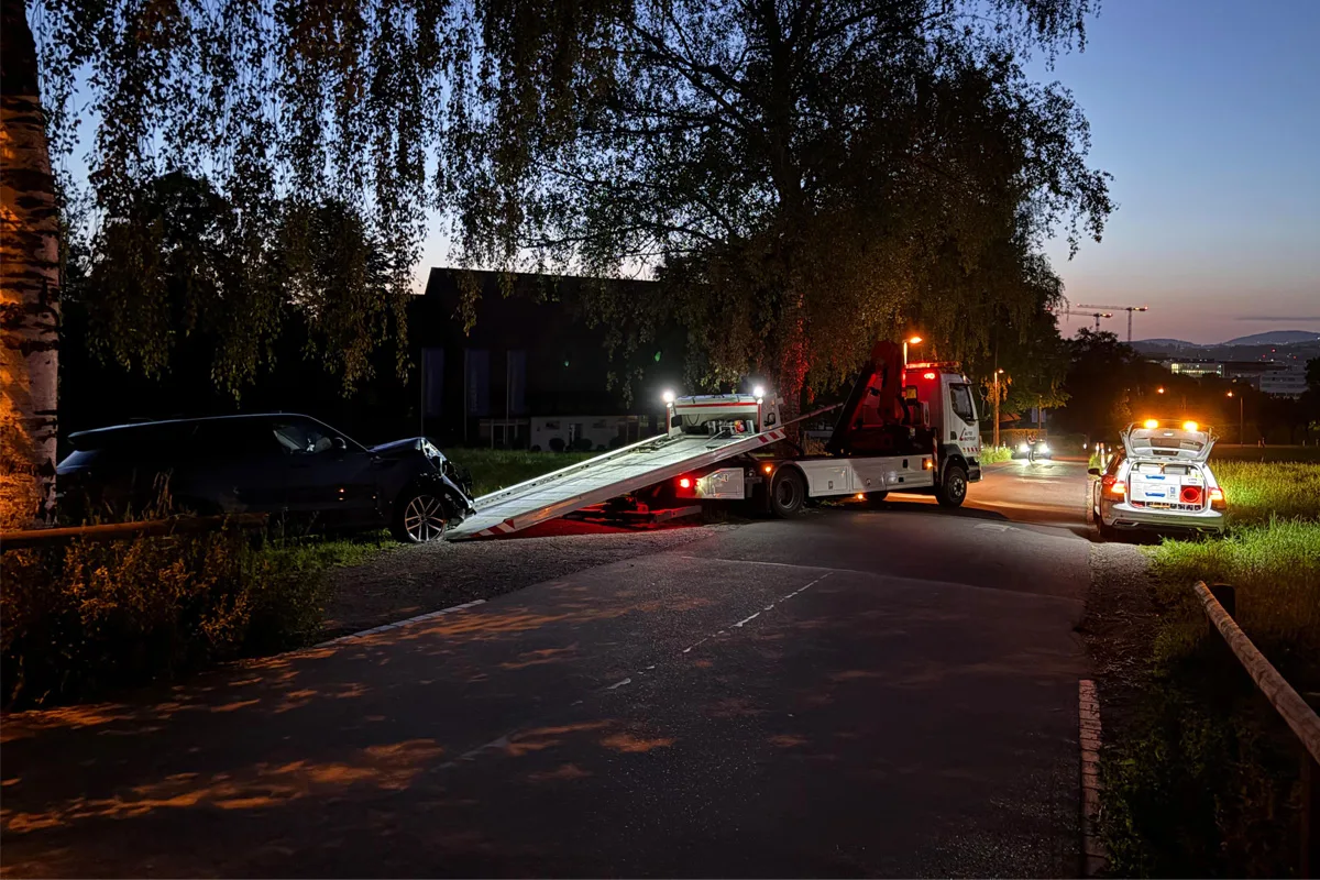 Bei Dunkelheit wird ein Auto von einem Abschleppwagen aufgeladen. Ein Polizeifahrzeug mit eingeschaltetem Blaulicht sichert die Stelle.