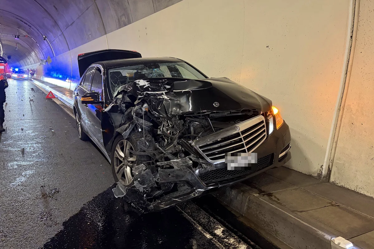 Ein schwarzes Auto ist im Tunnel stark beschädigt. Die Vorderfront ist stark deformiert.