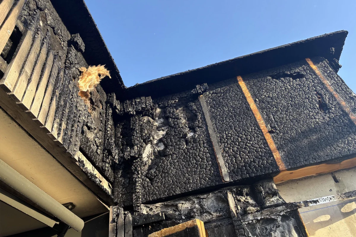 Ein nahe Aufnahme einer stark verbrannten Gebäudefassade. Markante Brandspuren und Aschereste sind sichtbar.