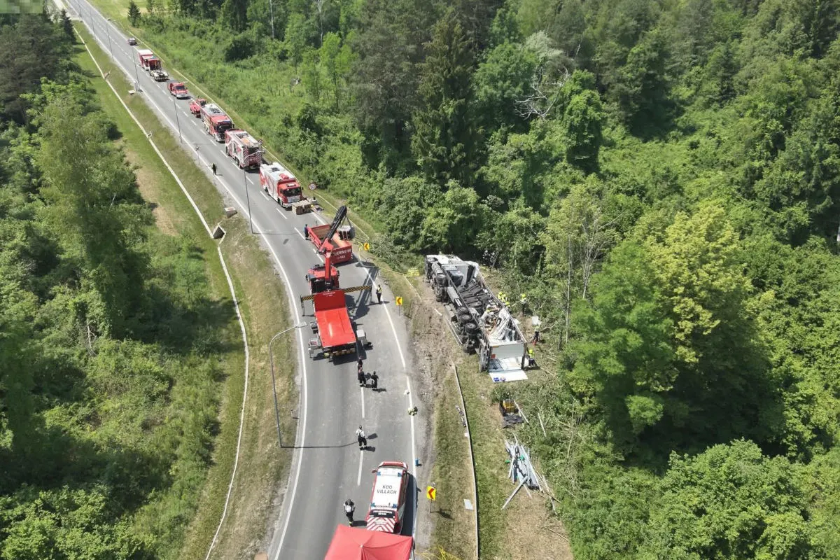Auf einer Landstraße stehen mehrere rote Einsatzfahrzeuge. Ein umgestürzter Lastwagen liegt rechts neben der Straße im Grünen. Feuerwehrleute sind bei der Bergung.